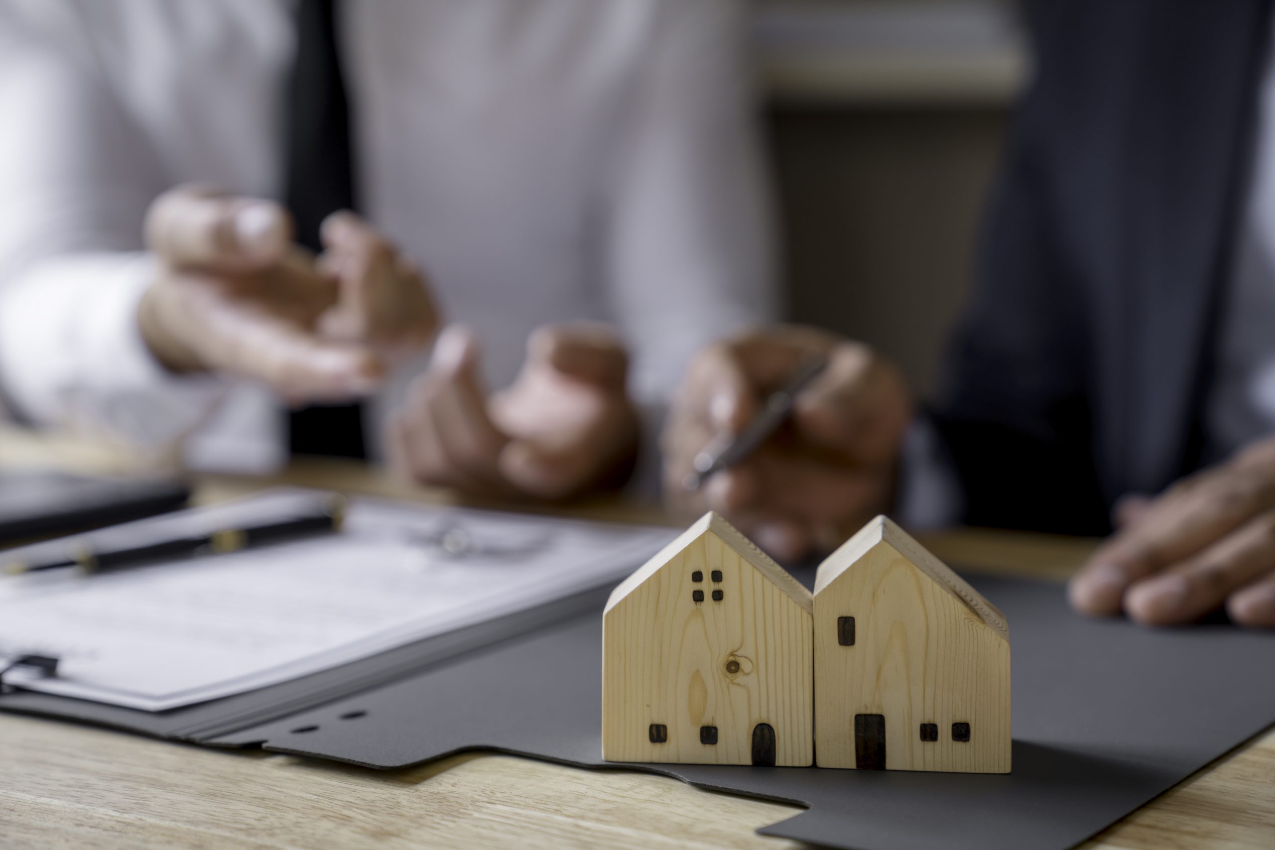 Discussion With A Real Estate Agent, a businesswoman signing a contract for Insurance protecting house, a real estate home is pointing to insurance contract signing and are explaining to customers.